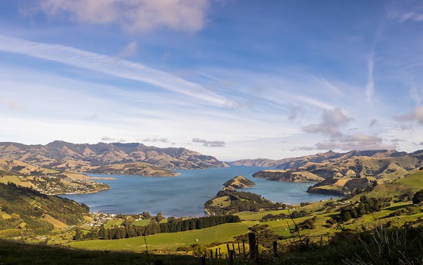 Akaroa Harbour view with surrounding hills, ideal for dolphin cruise tours.