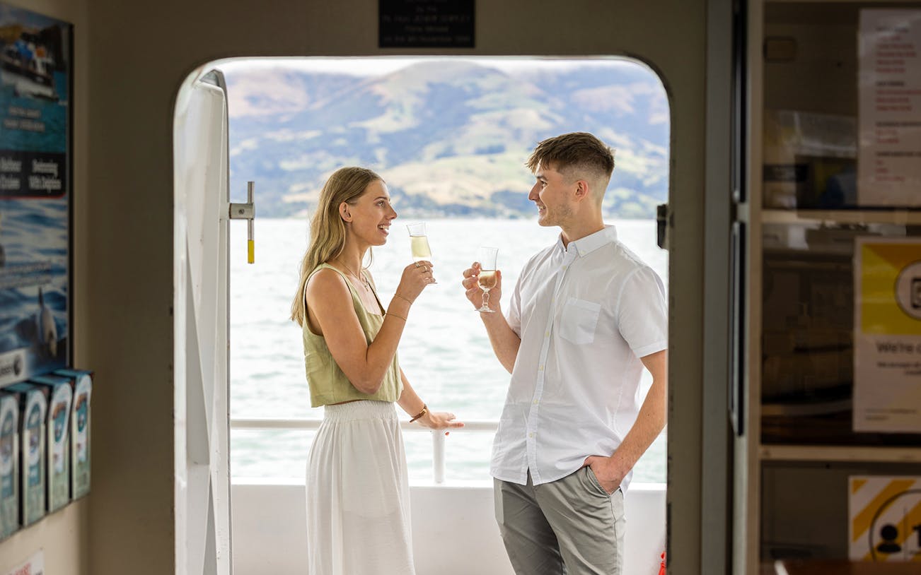Couple enjoying drinks on a boat during Dolphin & Nature Cruise in Akaroa.