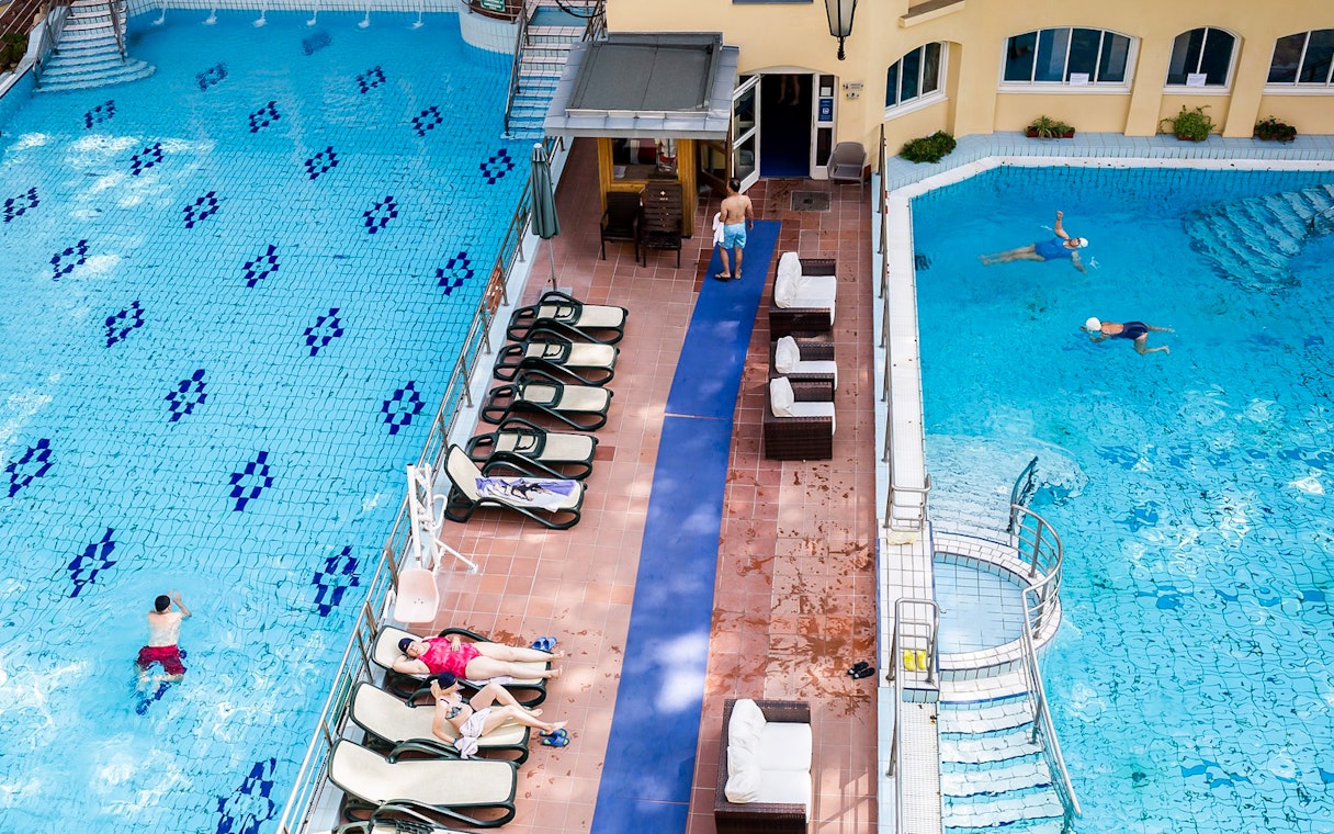Lukacs Thermal Bath pool in Budapest with swimmers and sunbathers.