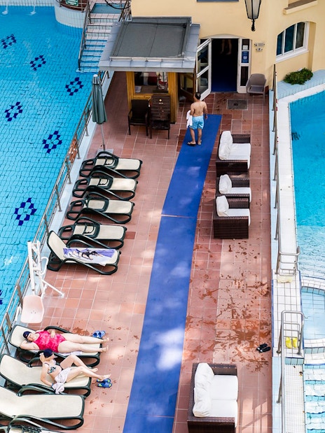 Lukacs Thermal Bath pool in Budapest with swimmers and sunbathers.