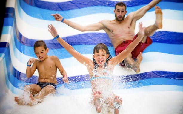 Children and an adult enjoying a water slide at Aquaworld Water Park, Budapest.