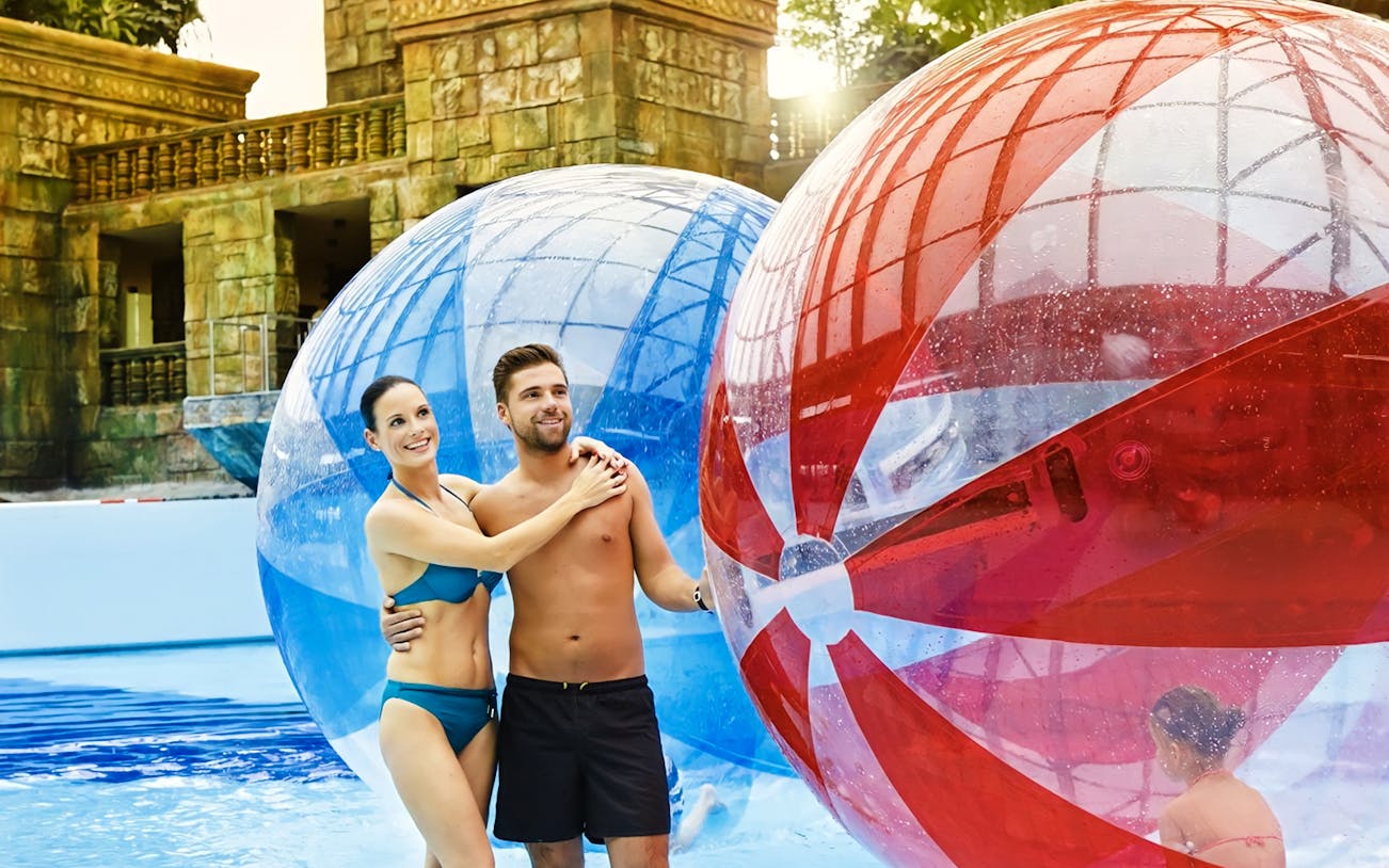 Couple enjoying giant inflatable balls at Aquaworld Water Park, Budapest.