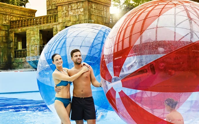 Couple enjoying giant inflatable balls at Aquaworld Water Park, Budapest.
