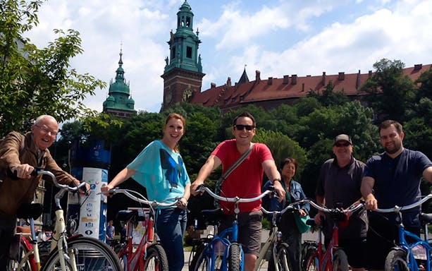 Group of cyclists on a city tour with historic architecture in the background.