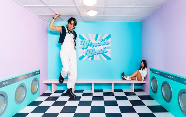 Visitors posing in a colorful laundry-themed room at Studio of Wonders.