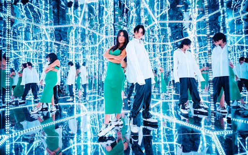 Visitors in a mirrored room at Studio of Wonders, surrounded by reflections and neon lights.