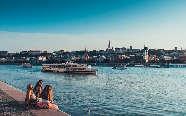 Boat tour on the Danube River in Budapest with cityscape in the background.