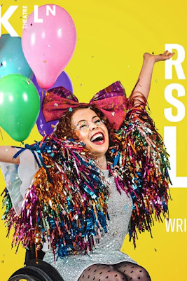 Performer in colorful costume with balloons, promoting "Reasons You Should(n’t) Love Me" at Kiln Theatre.