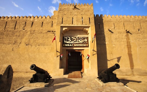 Dubai Museum entrance with cannons and flags, part of Snapshot Tour of Dubai.