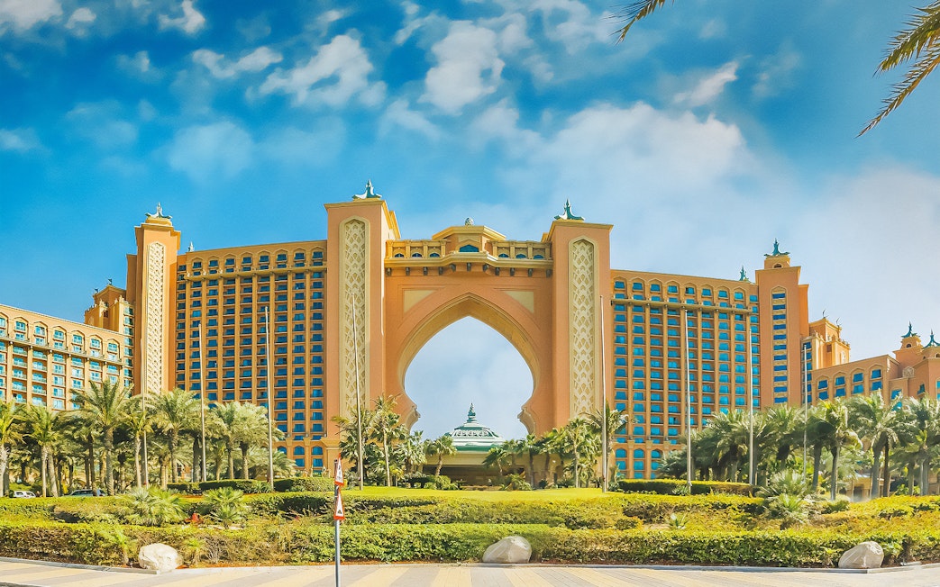 Atlantis The Palm hotel in Dubai with palm trees and blue sky.