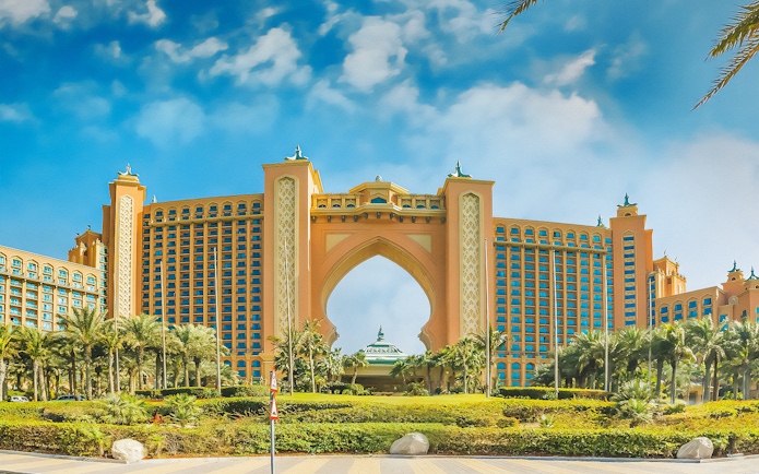 Atlantis The Palm hotel in Dubai with palm trees and blue sky.
