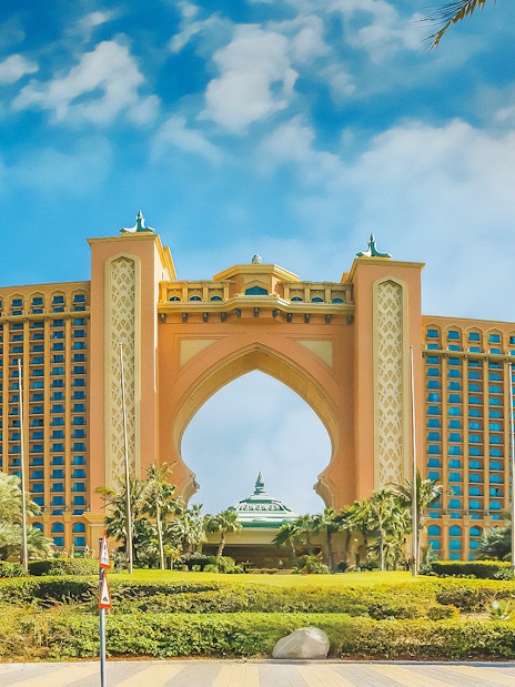Atlantis The Palm hotel in Dubai with palm trees and blue sky.