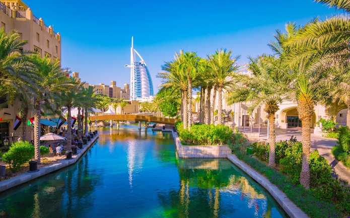 Canal view with palm trees and Burj Al Arab in Dubai.