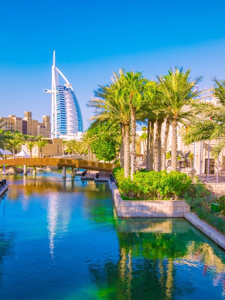 Canal view with palm trees and Burj Al Arab in Dubai.