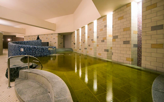 Spa LaQua indoor pool area in Tokyo, featuring tiled walls and a curved seating area.