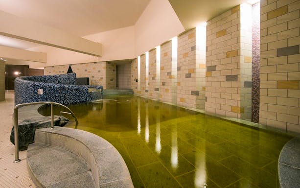 Spa LaQua indoor pool area in Tokyo, featuring tiled walls and a curved seating area.