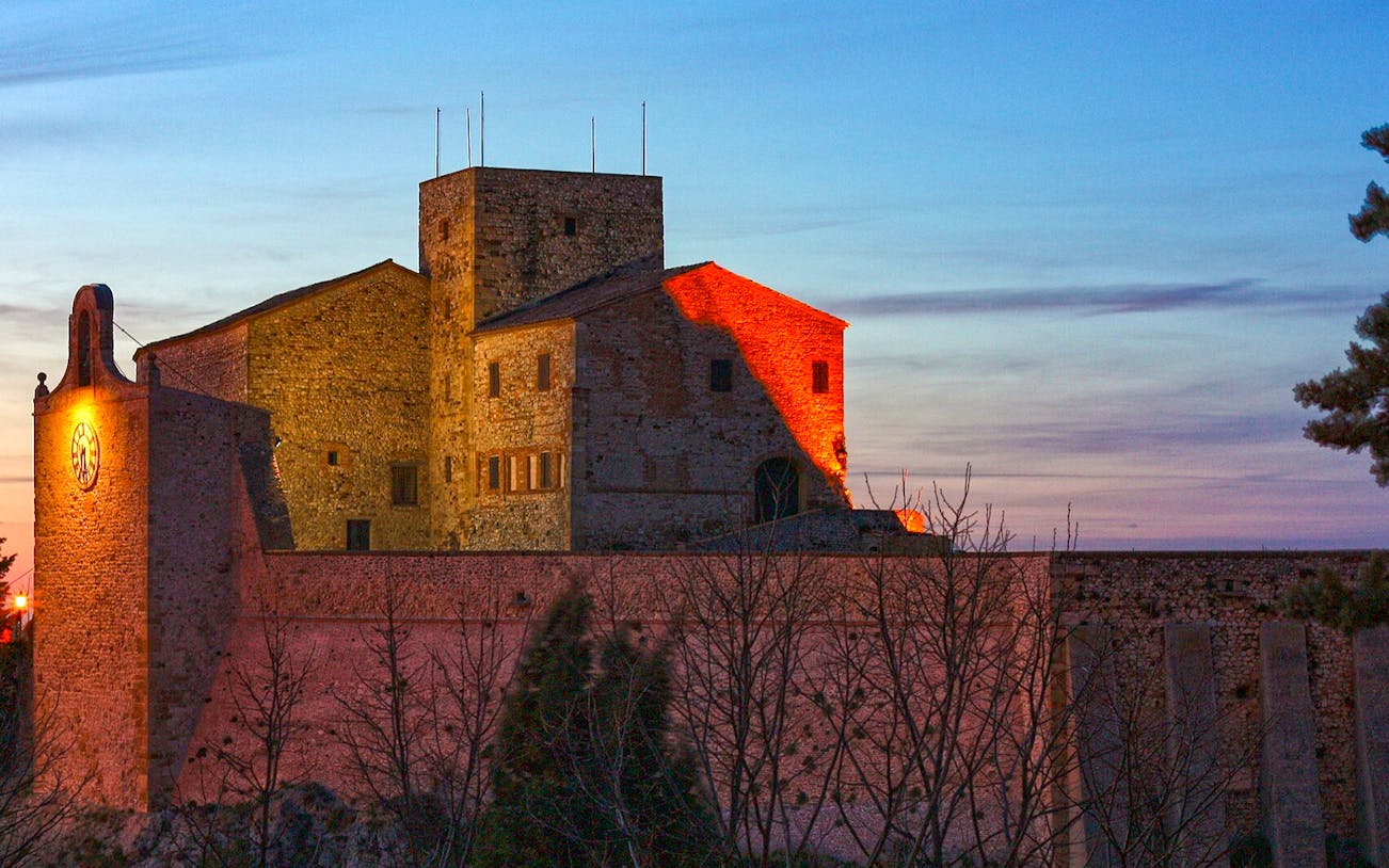 Rocca Malatestiana in Rimini at sunset with illuminated stone walls.
