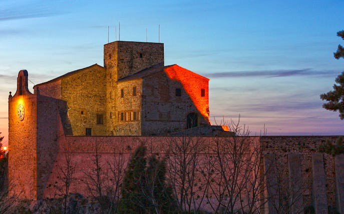 Rocca Malatestiana in Rimini at sunset with illuminated stone walls.