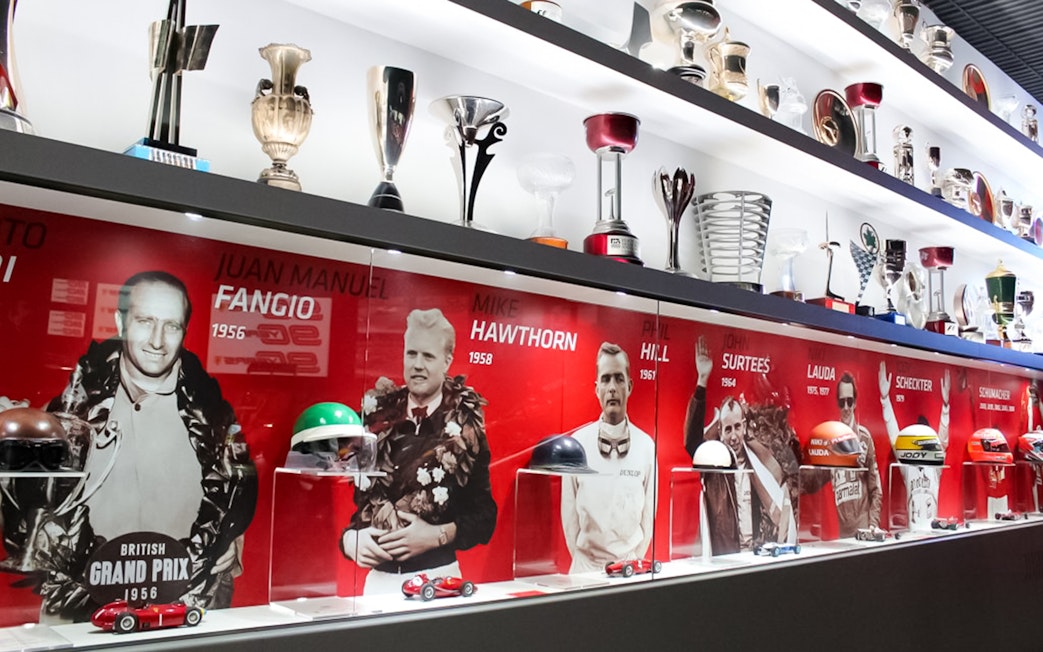 Trophies and racing memorabilia at Ferrari Museum Maranello, featuring famous drivers.