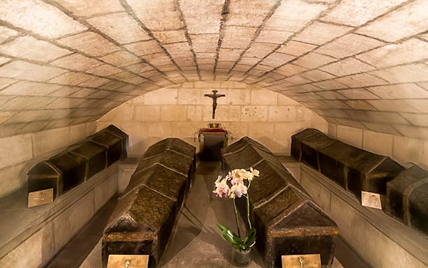 Royal Chapel of Granada crypt with ornate coffins and a cross.