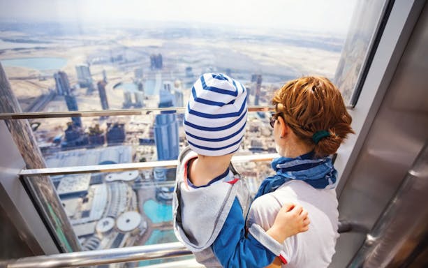 Mother and child viewing Dubai skyline from Burj Khalifa observation deck.