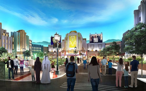 Visitors walking through Warner Bros. World Abu Dhabi with themed buildings and Justice League sign.