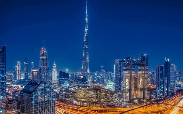 Dubai skyline at night featuring the illuminated Burj Khalifa, part of a private night tour with dining.