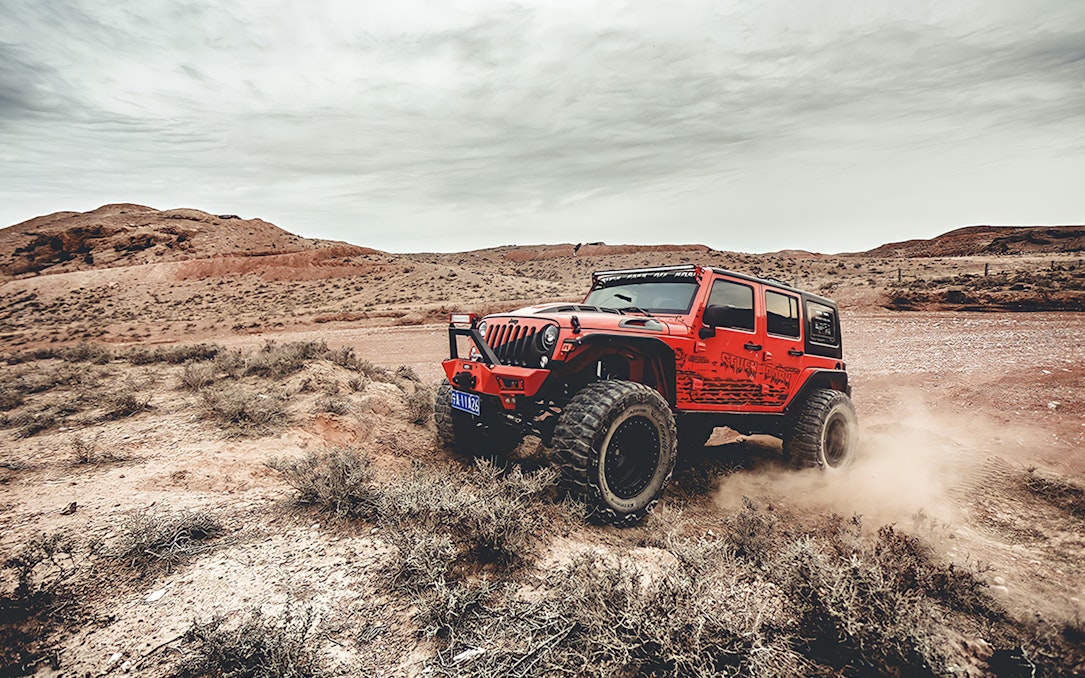 Red Jeep driving off-road in Cappadocia landscape during guided tour.