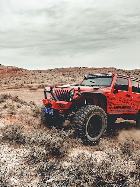 Red Jeep driving off-road in Cappadocia landscape during guided tour.