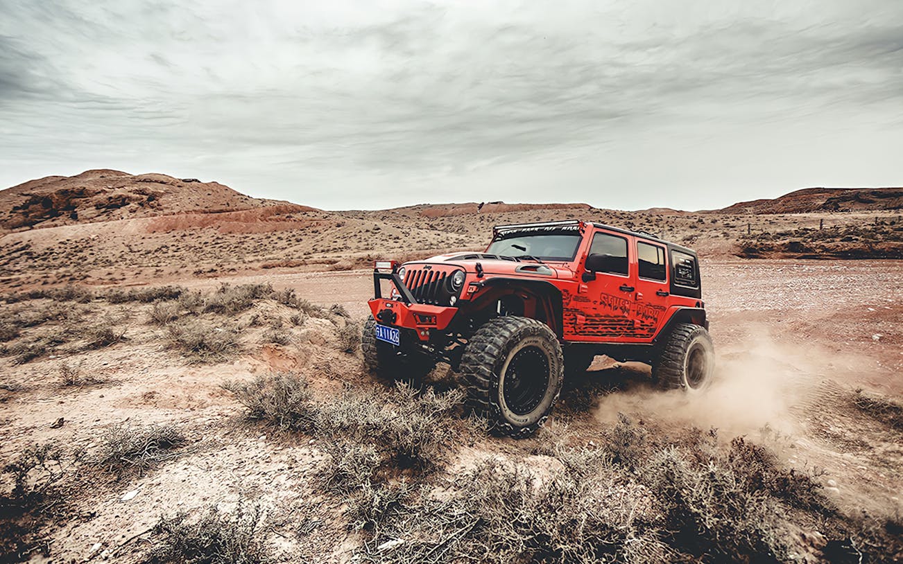 Red Jeep driving off-road in Cappadocia landscape during guided tour.