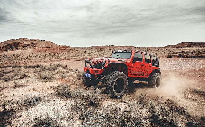 Red Jeep driving off-road in Cappadocia landscape during guided tour.