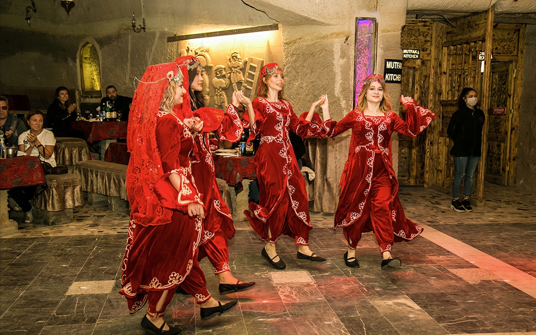 Dancers in traditional attire performing at a cave restaurant in Cappadocia.