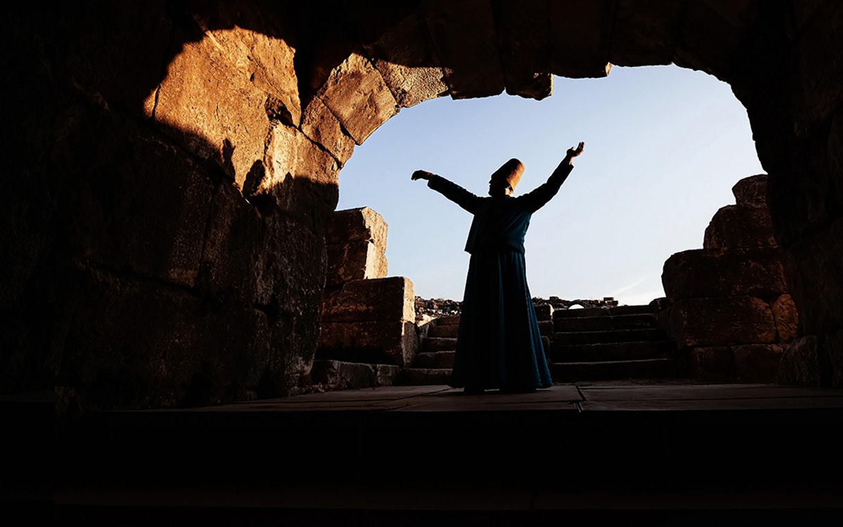Whirling dervish performing in ancient stone archway, Cappadocia.