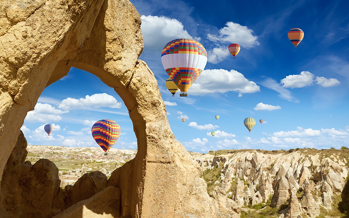 Hot air balloons over Cappadocia rock formations during Heart of Cappadocia Private Tour.