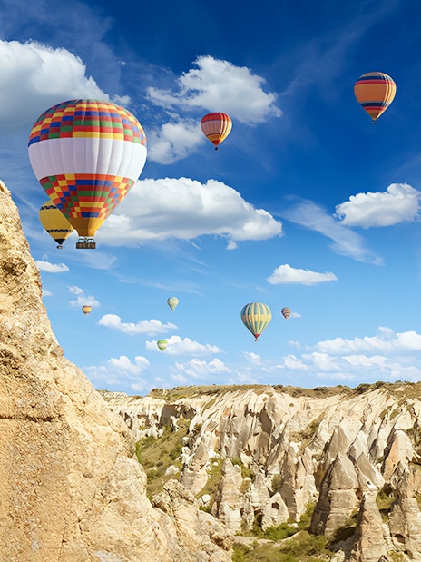 Hot air balloons over Cappadocia rock formations during Heart of Cappadocia Private Tour.