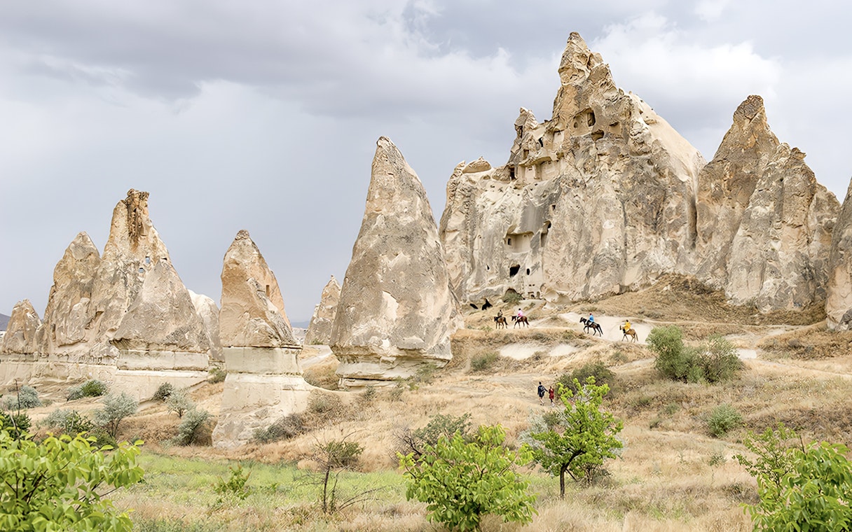 Cappadocia rock formations with people on horseback during Heart of Cappadocia Private Tour.