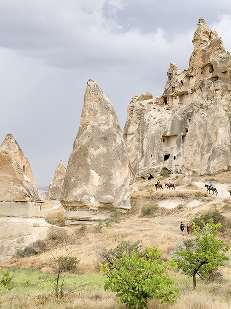 Cappadocia rock formations with people on horseback during Heart of Cappadocia Private Tour.