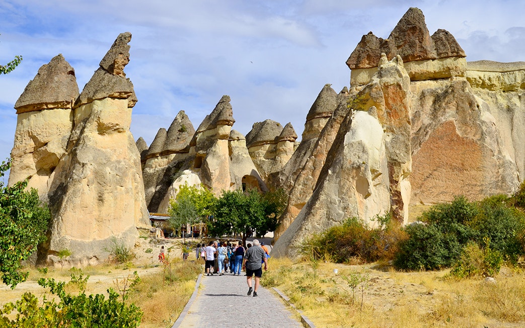 Tourists walking through rock formations at Göreme Open-Air Museum, Cappadocia.