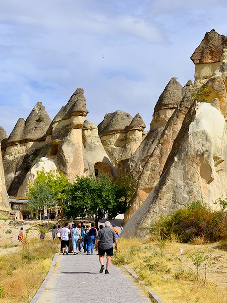Tourists walking through rock formations at Göreme Open-Air Museum, Cappadocia.