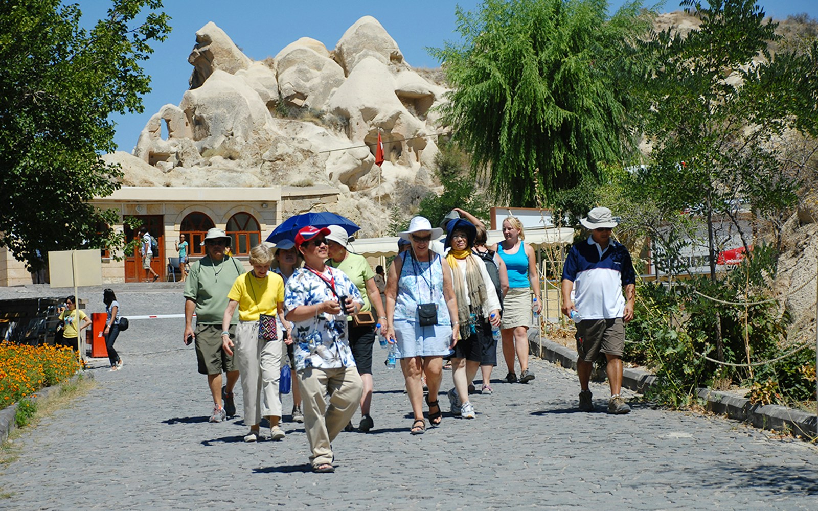 Tourists walking at Göreme Open-Air Museum, Cappadocia, with rock formations in the background.