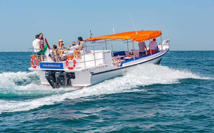 Boat with tourists cruising on Dubai waters, part of Atlantis Scenic Cruise experience.