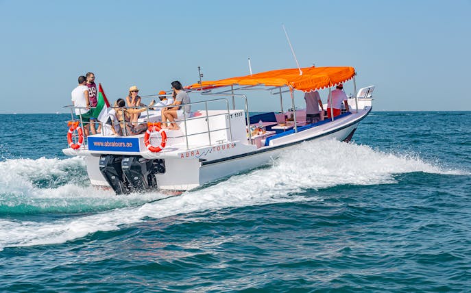 Boat with tourists cruising on Dubai waters, part of Atlantis Scenic Cruise experience.