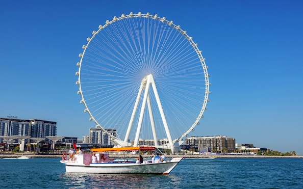Boat cruising near Ain Dubai Ferris wheel on Atlantis Scenic Cruise in Dubai.