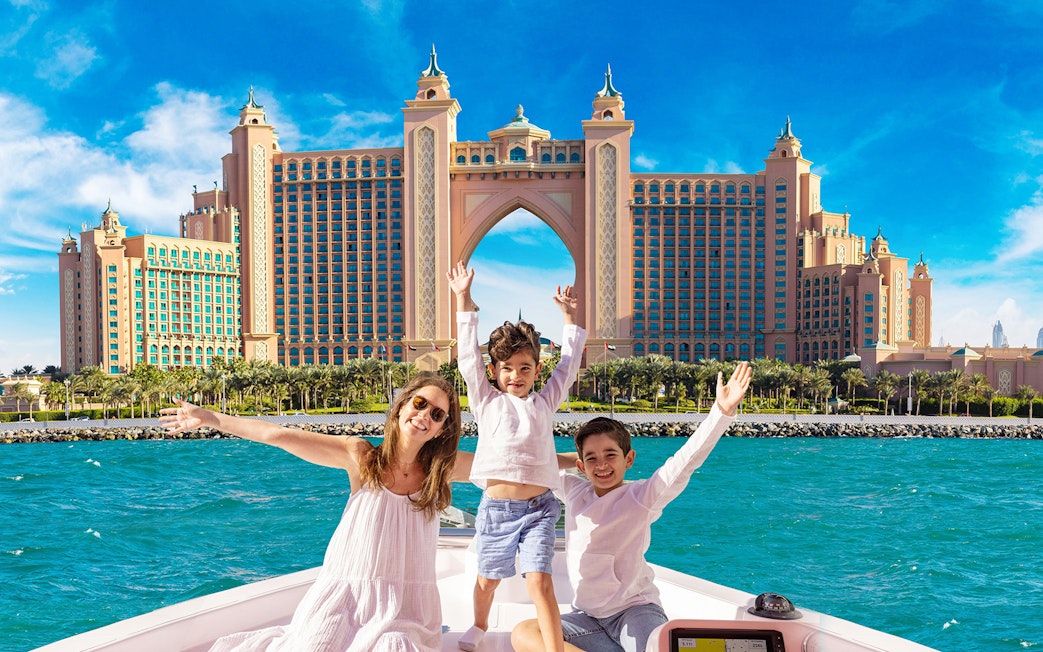 Family enjoying Atlantis Scenic Cruise with Atlantis The Palm in Dubai in the background.
