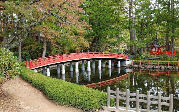 Red bridge over pond in Japanese garden, Nankai Railway tour.