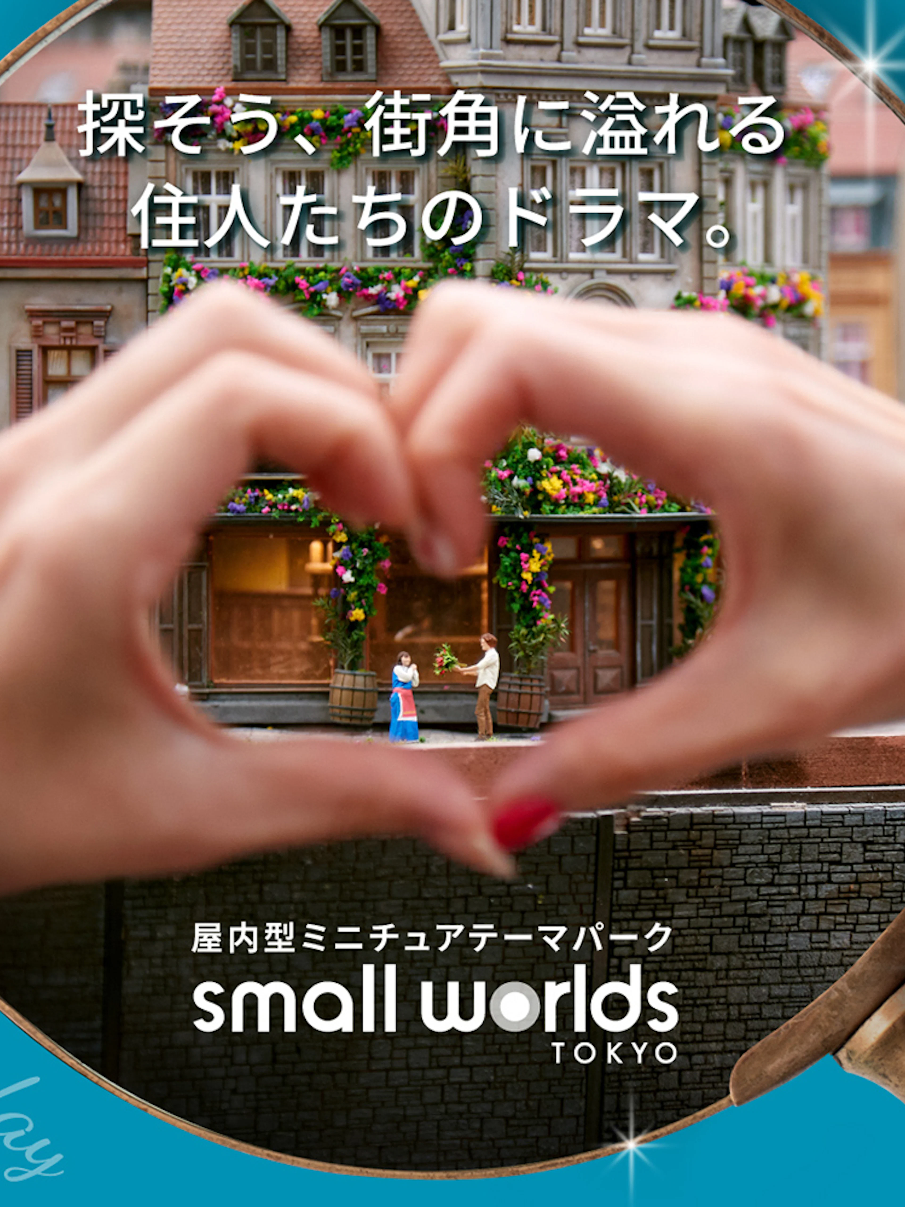 Miniature scene at Small Worlds Tokyo with hands forming a heart around tiny figures.