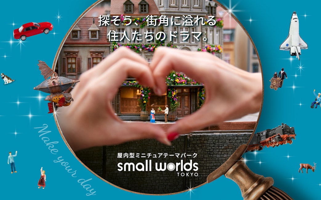 Miniature scene at Small Worlds Tokyo with hands forming a heart around tiny figures.