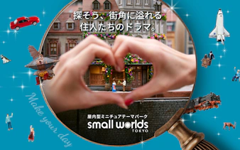 Miniature scene at Small Worlds Tokyo with hands forming a heart around tiny figures.