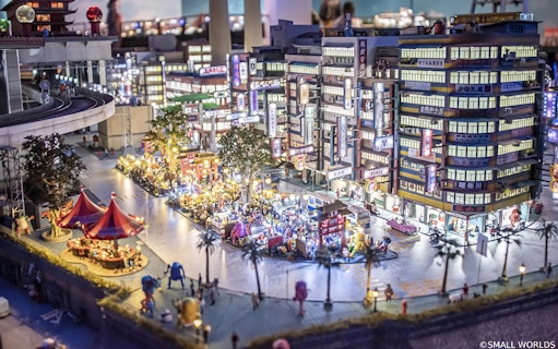 Miniature cityscape with bustling street market at Small Worlds Tokyo.