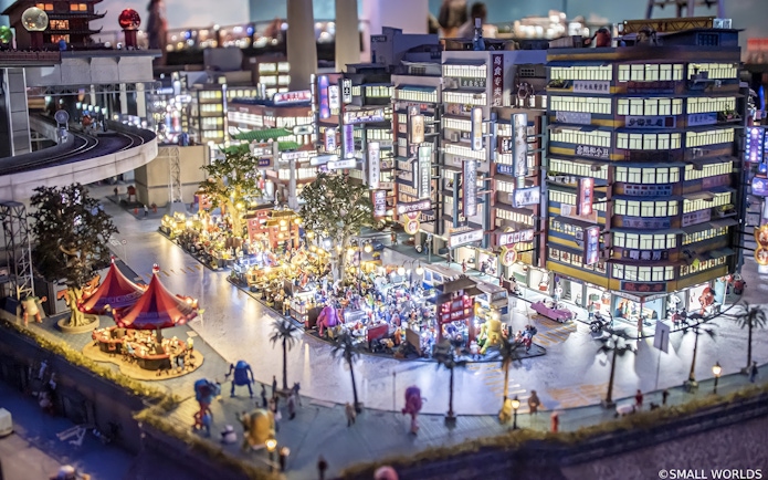 Miniature cityscape with bustling street market at Small Worlds Tokyo.